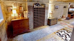 Een rustieke kamer met met baksteen beklede muren, een houten kast, een wijnrek en een kamerbreed tapijt met een patroon.