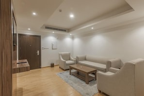 A modern living room with a sofa, armchairs, a coffee table, and a wooden floor. - Myrtle (Riyadh)