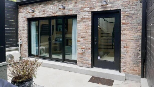 A building with a brick facade, large glass sliding doors, and a small balcony.