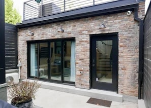 A building with a brick facade, large glass sliding doors, and a small balcony.