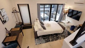 A hotel room with a bed, a desk, a chair, a TV, and a view of the outside. - Curious Carriage Rooftop in Shaw (Washington)