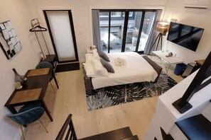 A hotel room with a bed, a desk, a chair, a TV, and a view of the outside. - Curious Carriage Rooftop in Shaw (Washington)