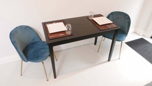 A table with two chairs, a glass, and a small jar.