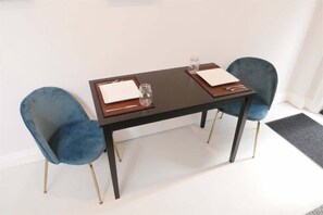 A table with two chairs, a glass, and a small jar.