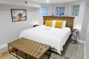 Un dormitorio con una cama grande, un cabecero de madera, un banco y un cuadro en la pared.