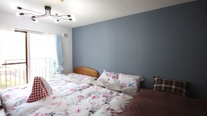 A bedroom with a bed, a wooden headboard, a ceiling light fixture, and a view of the outdoors through a sliding door. - Susukino Own It (Sapporo)