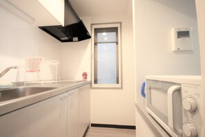 A compact kitchen with a stainless steel sink, a microwave, and a window.