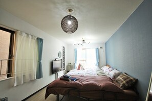 A bedroom with a bed, a ceiling fan, a television, and a window with curtains. - Susukino Own It (Sapporo)