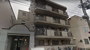 A multi-story residential building with balconies, a mail slot, and bicycles parked outside. - Susukino Own It (Sapporo)
