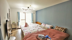 A bedroom with a bed, a desk, a chair, a window with curtains, and a ceiling light fixture. - Susukino Own It (Sapporo)