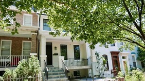 A row of townhouses with a central staircase, a small porch, and a brick wall. - No More Looking-Parking (Washington)