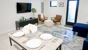 A modern living room with a dining table set for four, a TV mounted on the wall, and a large window with a view. - No More Looking-Parking (Washington)
