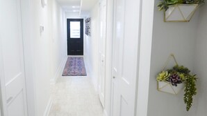 A hallway with white walls, a patterned rug, and two wall-mounted plant decorations. - No More Looking-Parking (Washington)