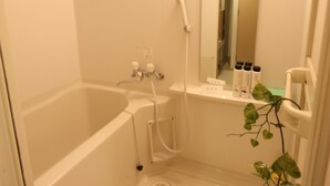 A small, white bathroom with a bathtub, a shower, and a sink. There are toiletries on the sink and a mirror above it.