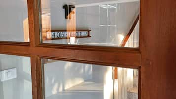 Un interno moderno con una porta in vetro, una scala e una targa con i numeri delle camere.