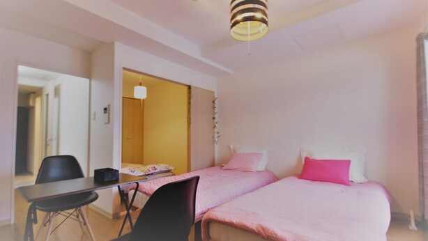 Un dormitorio con dos camas, un escritorio y una silla.