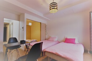 A bedroom with two beds, a desk, and a chair.