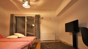Un dormitorio con cama, televisor de pantalla plana, calefacción y puerta corrediza de vidrio.
