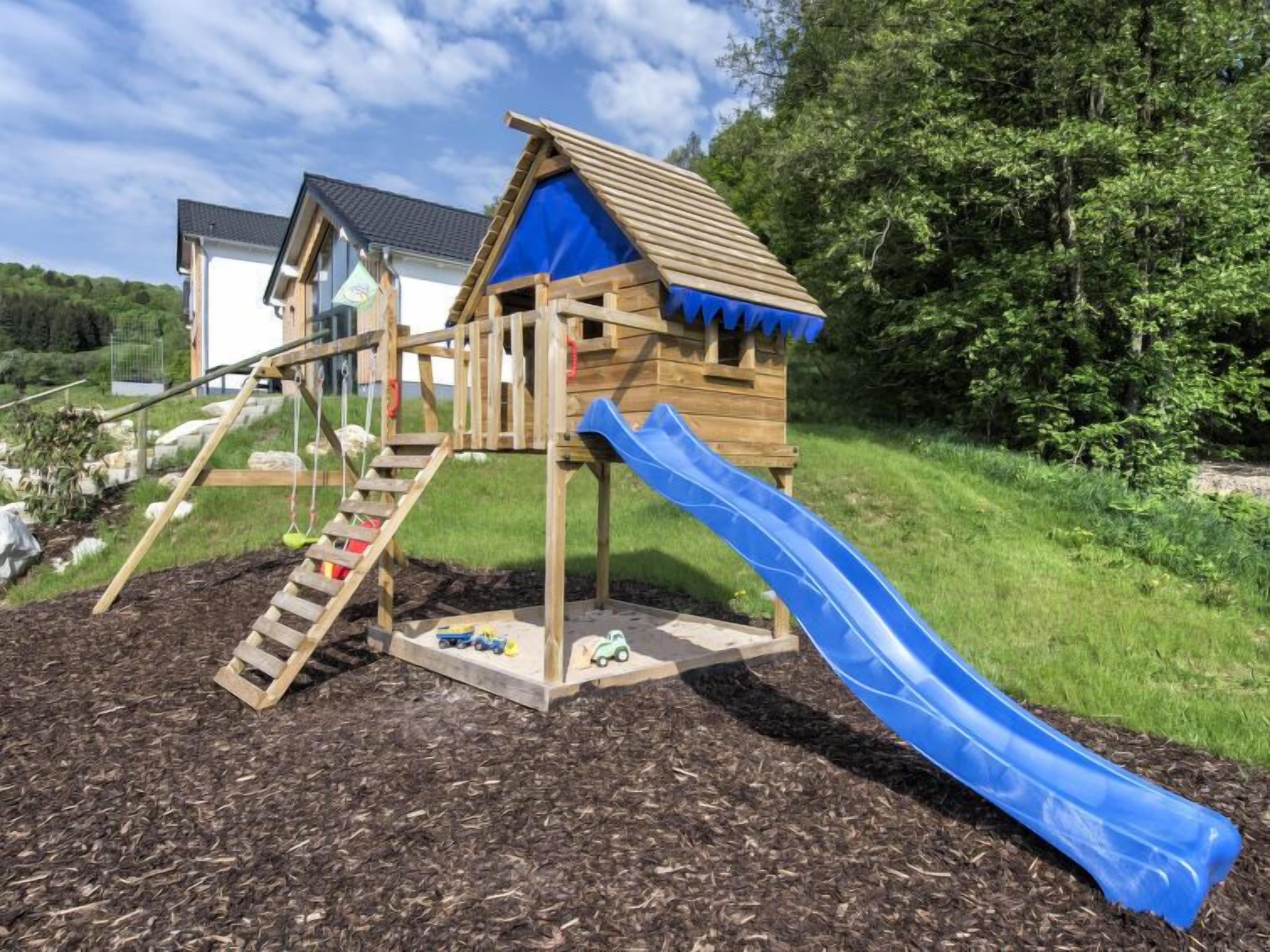 Eine Holzspielkonstruktion mit Rutsche und Kletterstufen.