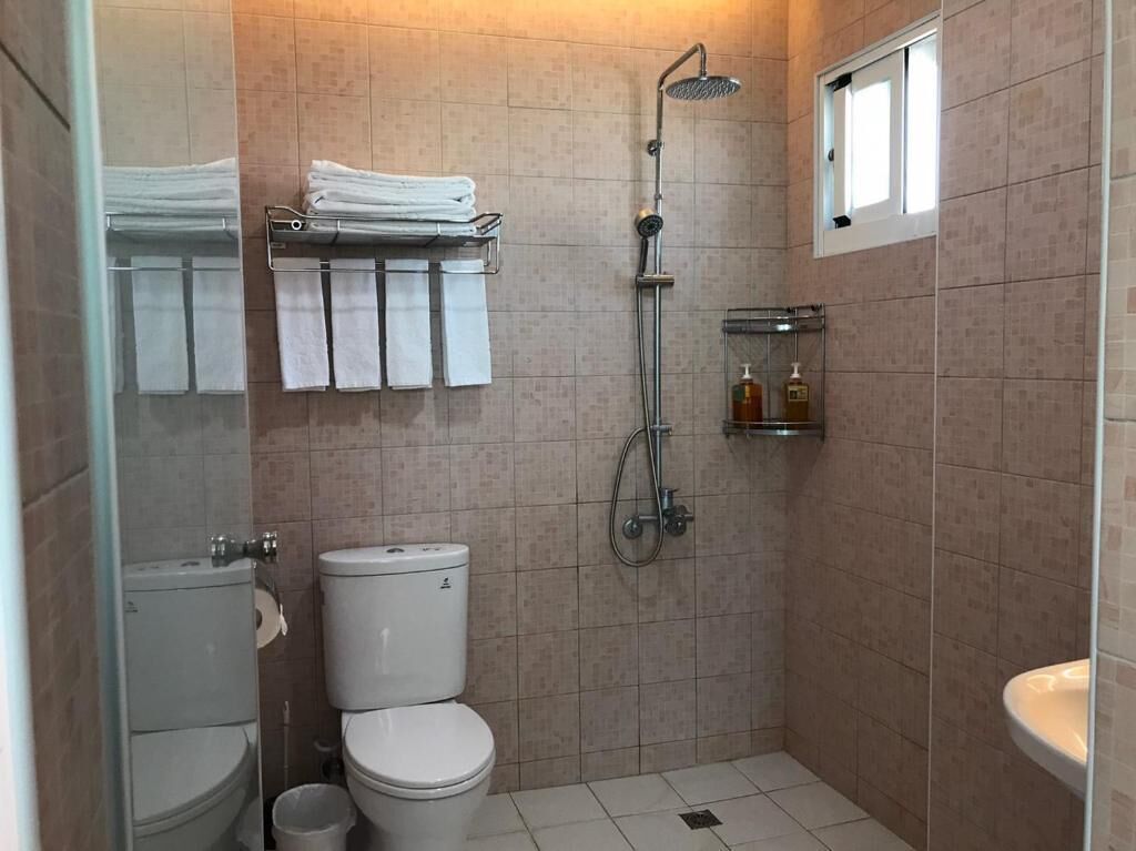 Un baño pequeño con azulejos, un inodoro, una ducha y un lavamanos.