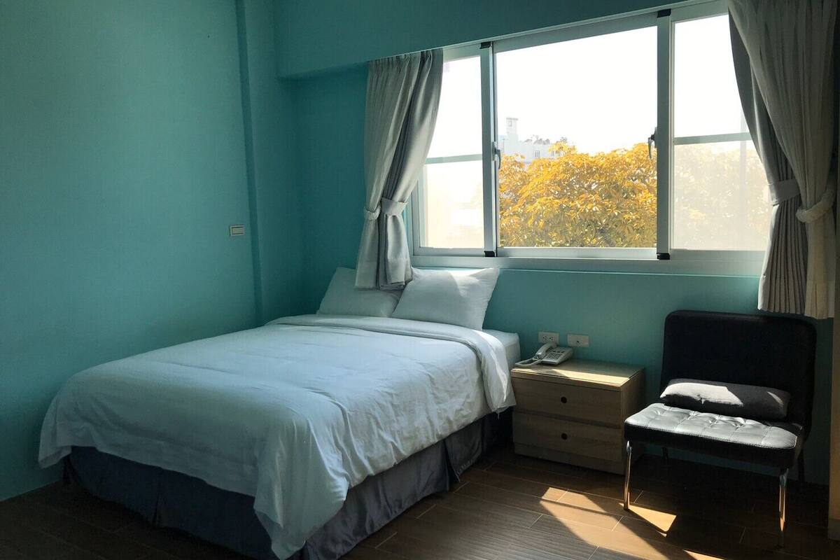 Quarto com cama, mesa de cabeceira e uma cadeira.