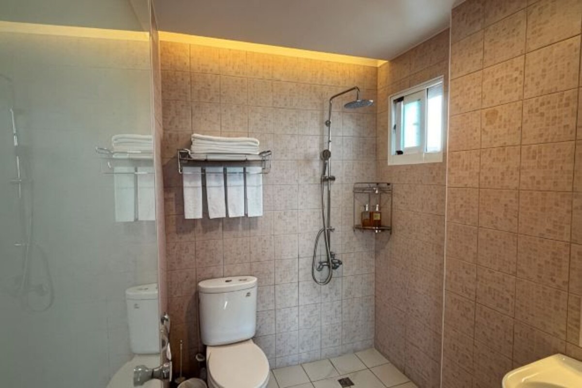 Une salle de bain avec des toilettes, une douche et une petite fenêtre.