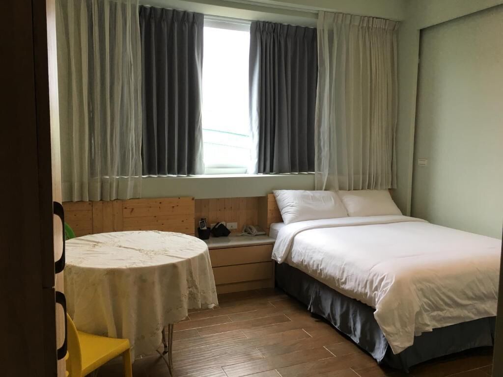 A small, cozy bedroom with a single bed, a round table, and a bench.