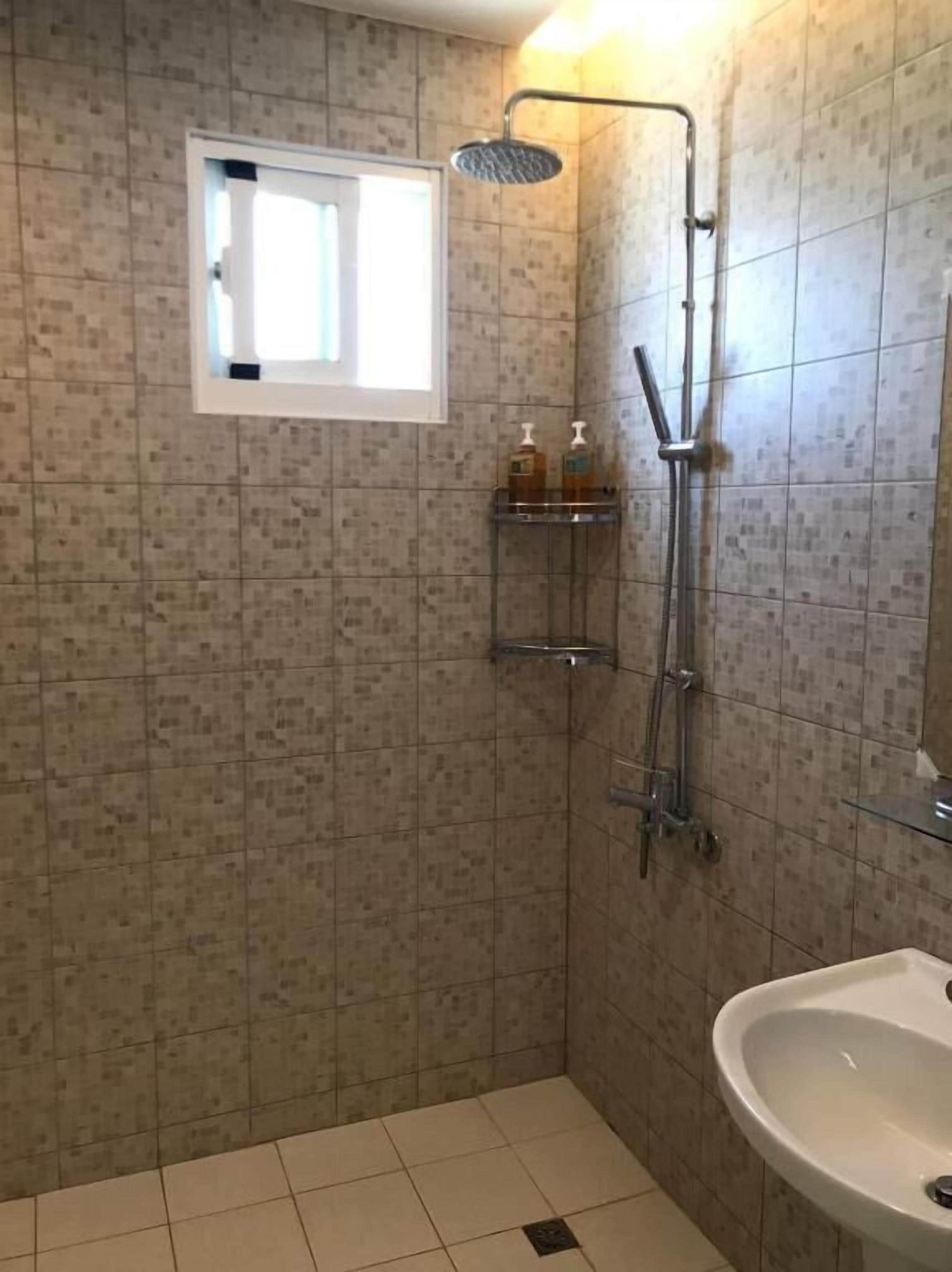 Un baño con ducha, lavabo y ventana.