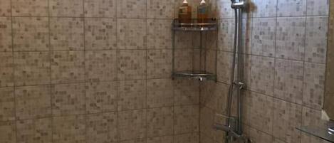 Un baño con ducha, lavabo y ventana.