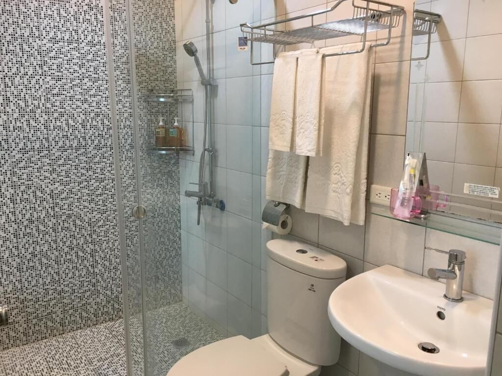 A bathroom with a glass shower enclosure, a toilet, a sink, and a towel rack.