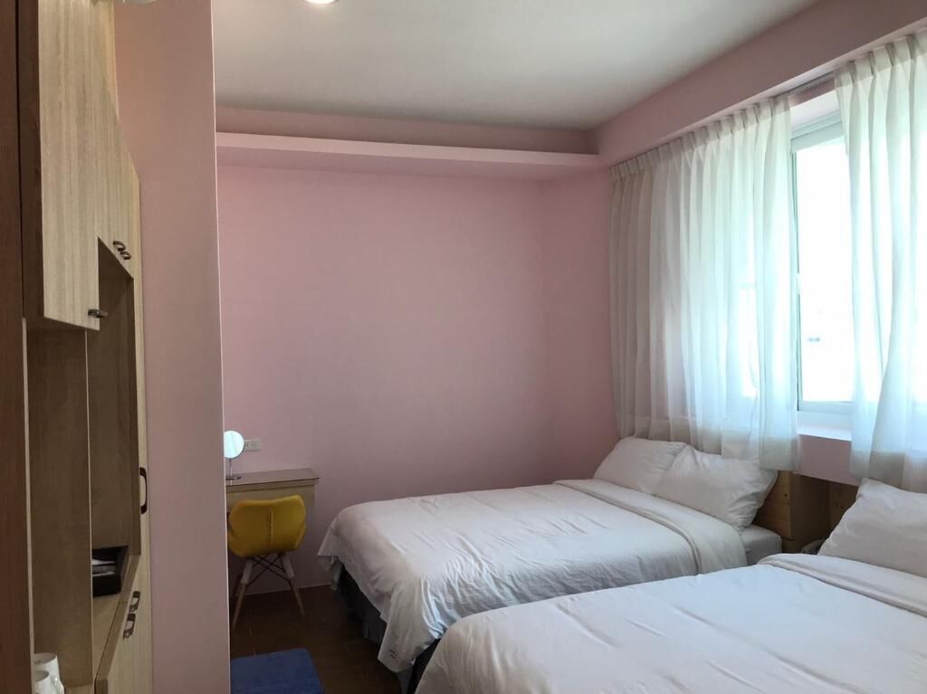 Een slaapkamer met twee bedden, een bureau, een stoel en een kledingkast.