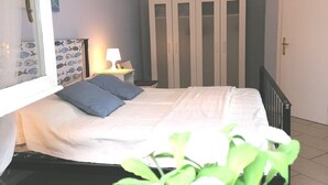 Um quarto com uma cama, uma mesa de cabeceira com abajur, um armário e uma janela com cortinas.