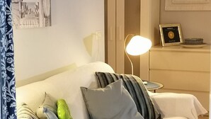 Quarto bem arrumado com cama, travesseiros, abajur e uma moldura com imagem no criado-mudo.