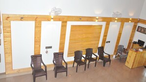 A reception area with wooden paneling, a reception desk, and several chairs. - Water View Holiday Retreat (Belur)