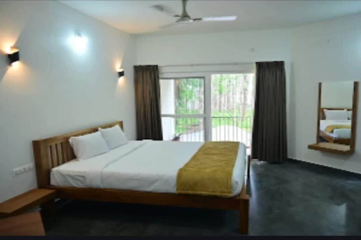 Ein Schlafzimmer mit einem Bett, einem Nachttisch, einem Spiegel und einem Fenster mit Vorhängen.