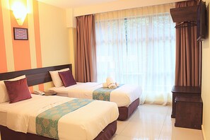 A hotel room with two beds, a nightstand, a lamp, and a window with curtains.