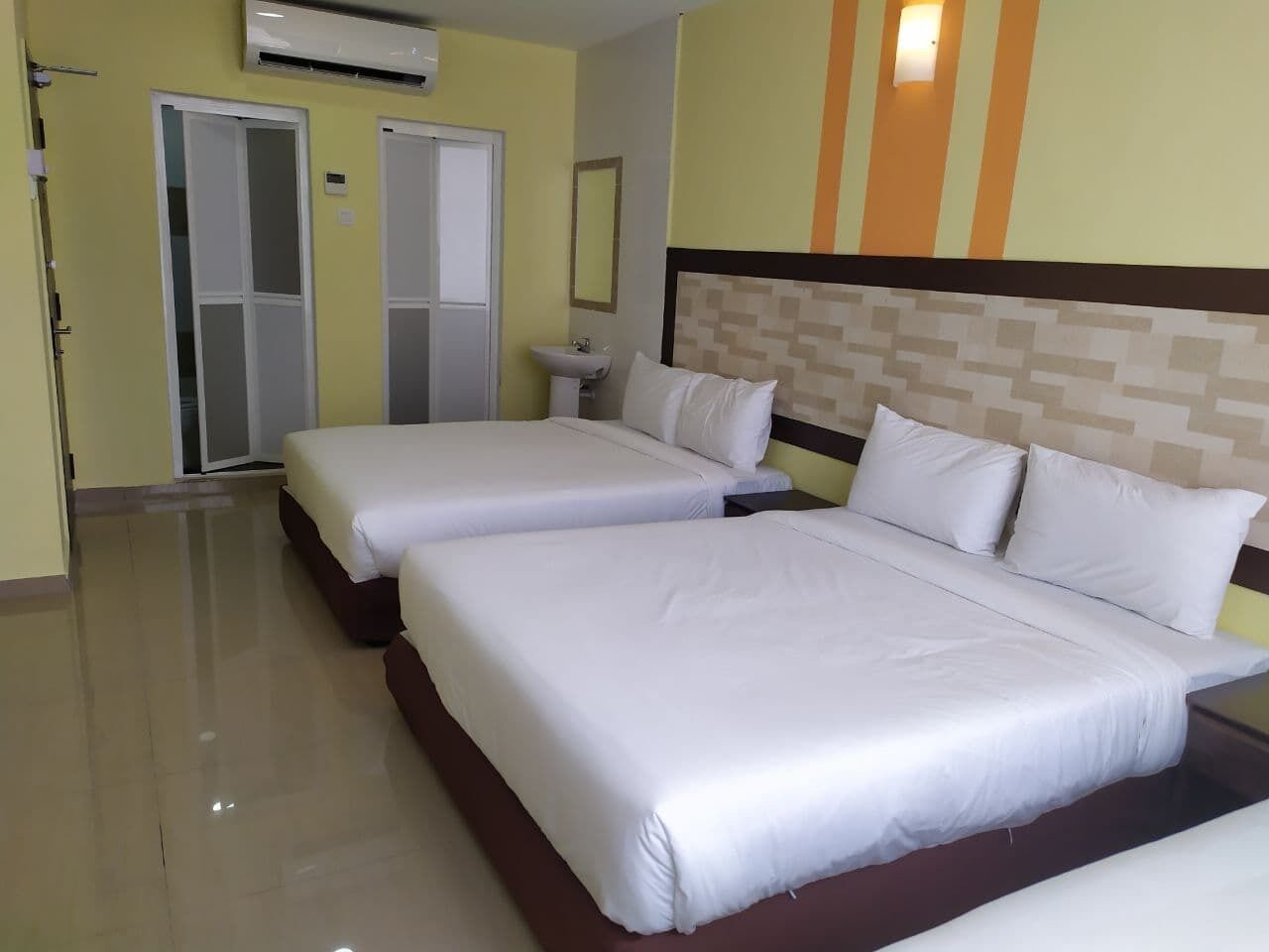 A hotel room with two beds, a bathroom, and a tiled floor.