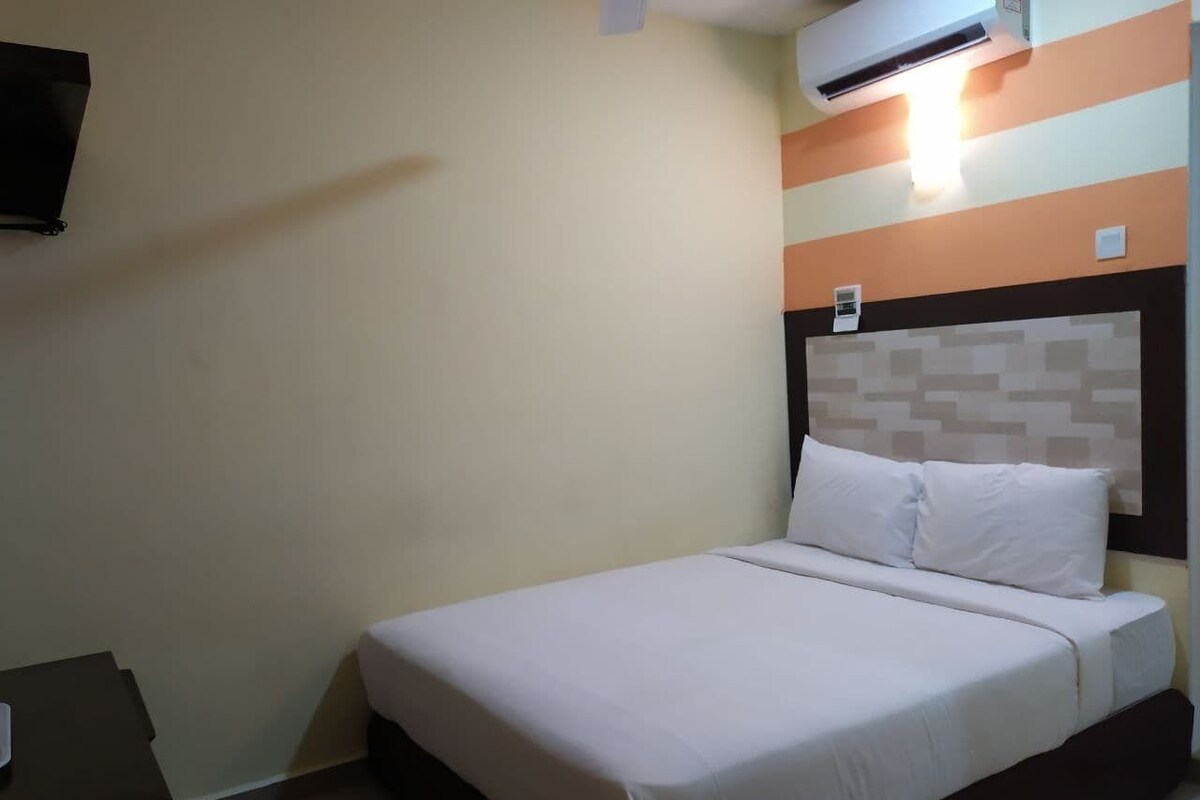 A single bed with white bedding, a headboard with a patterned design, and an air conditioning unit mounted on the wall.