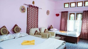 A bedroom with a bed, a sofa, a small table, and a window with curtains. - Kaziranga   homestay (Kohora)