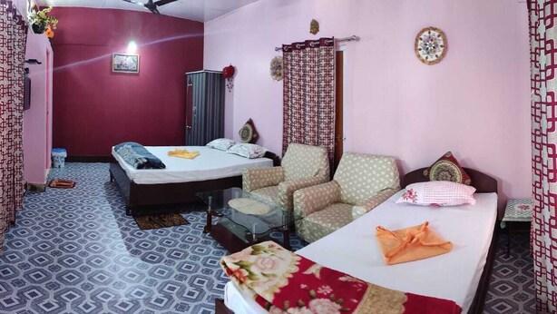 A bedroom with two beds, a chair, and a small table. - Kaziranga   homestay (Kohora)