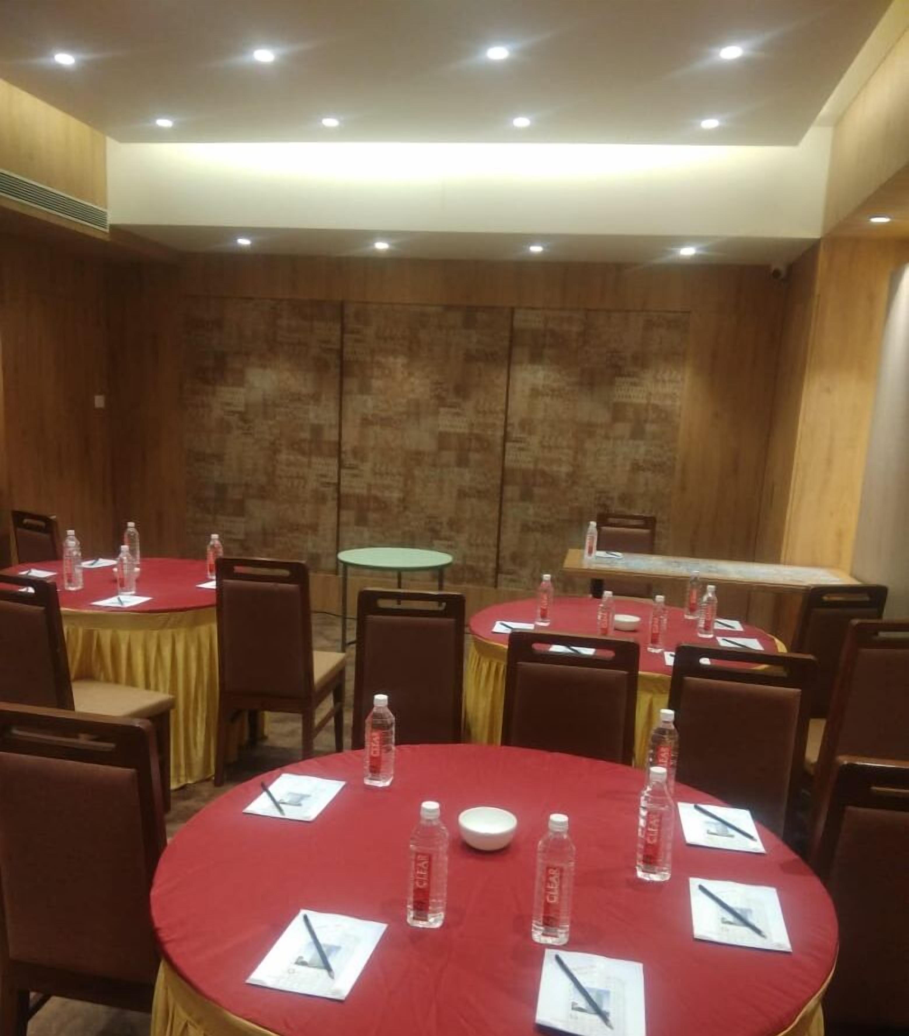 Una sala de conferencias con mesas redondas, sillas y botellas de agua.