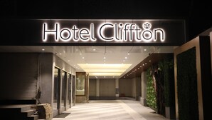 The entrance of Hotel Clifton with a modern design, featuring a prominent illuminated sign and a clean, well-lit pathway leading inside. - Hotel Cliffton (Mumbai)