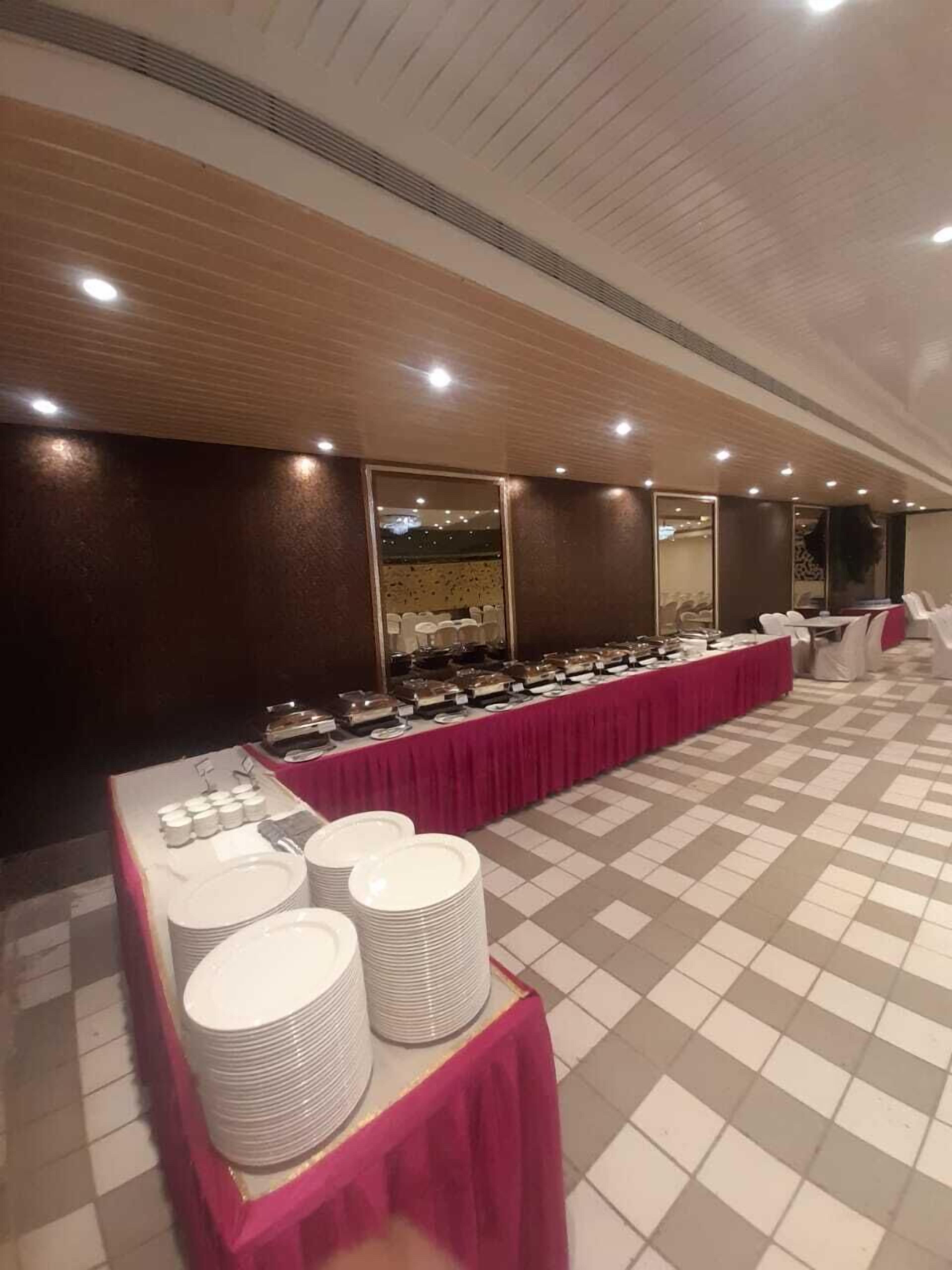 Un buffet est installé sur une longue table recouverte d’une nappe rose, avec des assiettes blanches et une variété de plats.