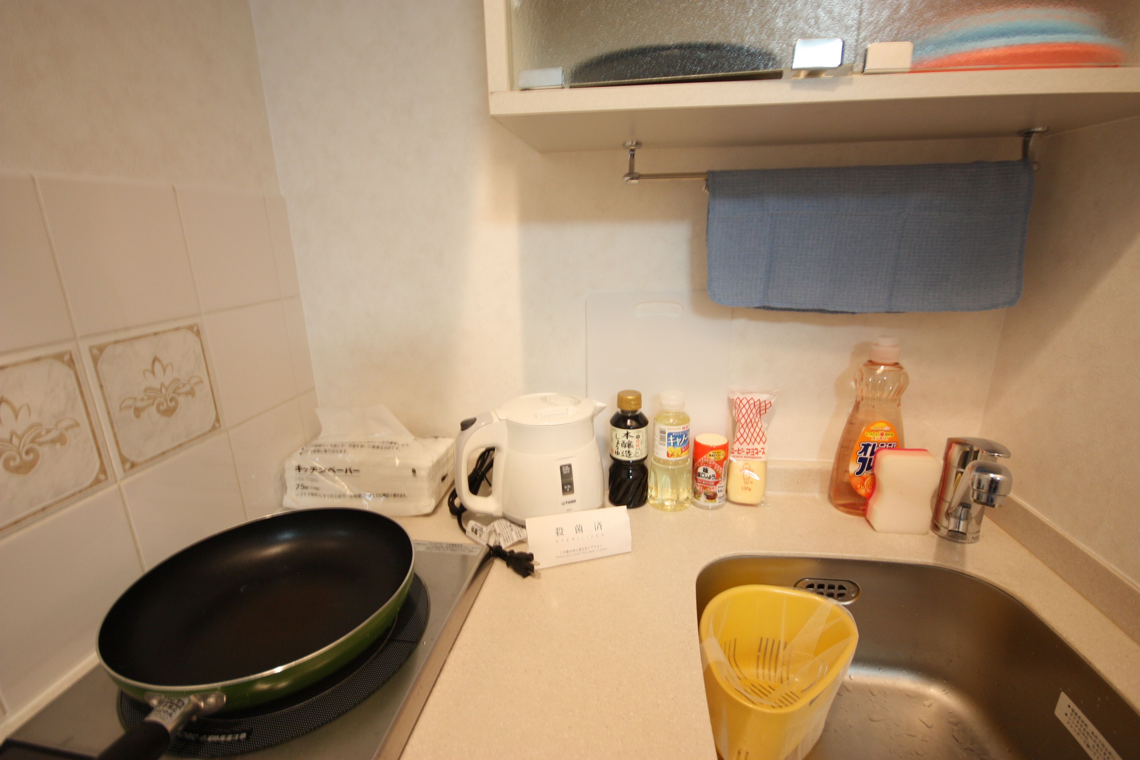 A kitchen with a stove, a kettle, a sink, and various kitchen items.