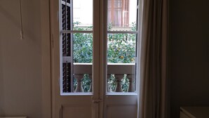 Una habitación con puerta que da a un balcón con vistas a zonas verdes y un edificio.