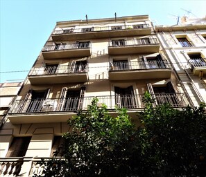 A multi-story building with balconies, a visible staircase, and a tree in the foreground. - Vacation rental flat restored for rent in Barcelona center, Gracia (Barcelona)