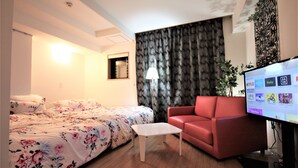 Une chambre d’hôtel avec un lit, un canapé rouge, une petite table et un téléviseur permettant d’accéder à différents services de diffusion en continu.