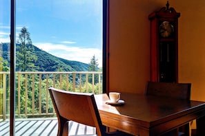 A balcony with a wooden table, a white cup, and a wooden chair. A wooden clock is visible on the wall. - Harriway Hotel Hakone (Hakone)