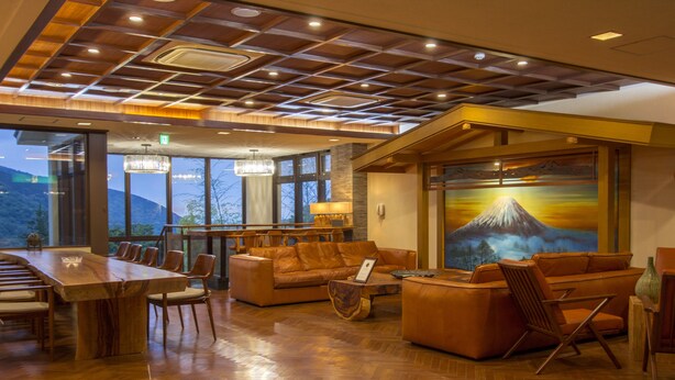 Ein geräumiger Raum mit einem großen Esstisch aus Holz, Ledersofas und einem großen Gemälde einer Berglandschaft.
