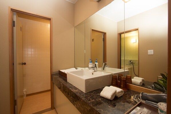 A modern bathroom with a large sink, mirror, and shower.